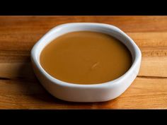 a white bowl filled with brown liquid on top of a wooden table