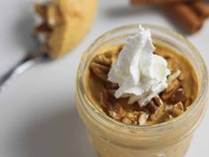 a glass jar filled with pudding and whipped cream on top of a table next to cinnamon sticks