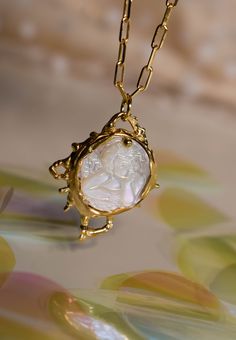 A mother of pearl angel/cupid cameo necklace on a intricate and detailed bezel. The part of the bezel holding the cameo is a bit free form, so it won't be exactly the same as the one pictured. The lovely formations around the cameo will be the same :) *Details The pendant is about 2.5x2cm (1x0.8in) The chain is about 40cm (1.3ft) all around You can choose between brass and sterling silver ♥ Every piece is carefully handcrafted in my studio in Athens ♥ ** The necklace pictured is not the exact on Luxury Gold Cameo Necklace, Intaglio Pendant Necklace For Wedding, Elegant Mother Of Pearl Medallion Necklace, Elegant Medallion Necklace In Mother Of Pearl, Ornate Round Necklace With Pearl Pendant, Ornate Coin Pendant Necklace As Gift, Ornate Round Necklaces With Pearl Pendant, Elegant Round Pendant Intaglio Necklace, Pearl Medallion Pendant Jewelry In Mother Of Pearl