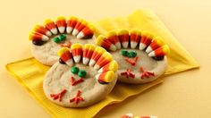 two cookies decorated like turkeys sitting on top of a yellow napkin next to candy