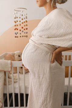 a pregnant woman standing next to her crib