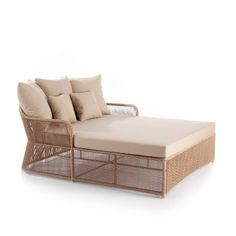 a wicker daybed with pillows on the top and bottom, in front of a white background