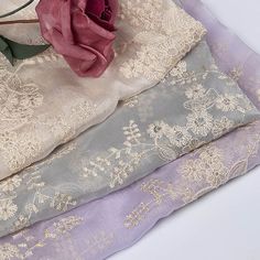 three different colors of fabric with flowers on them and one pink rose in the middle