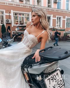 a woman in a white dress is sitting on a motorcycle