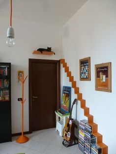 there is a room with some books on the wall and an orange stair case next to it