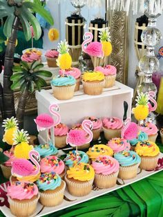 a table topped with lots of cupcakes covered in frosting