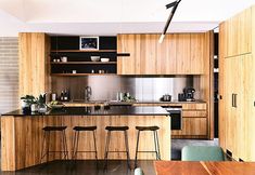 a kitchen with wooden cabinets and stools next to an island counter top in front of a brick wall