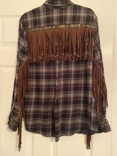 a plaid shirt with fringes hanging on a door