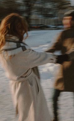 two people are walking in the snow with one holding onto another person's hand