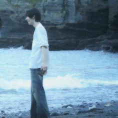 a man standing on top of a beach next to the ocean