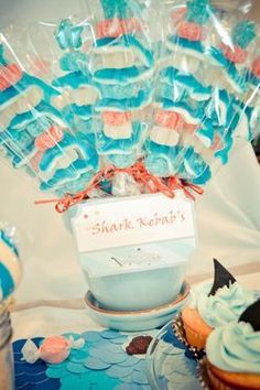 a table with cupcakes and candy in plastic wrappers that say shark ketchup