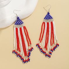 red, white and blue beaded earrings with fringes on top of a table