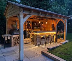 an outdoor bar is lit up at night with lights shining on the bars and stools