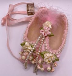 a pair of pink shoes with pearls and flowers