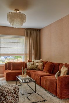 a living room filled with furniture and a chandelier hanging from the ceiling next to a window