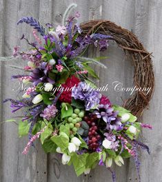 a wreath with flowers and greenery hanging on a fence