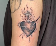 a tattoo with a heart and cross on it's arm that has flames coming out of it