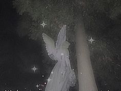 an angel statue in front of a tree with stars on it's back ground