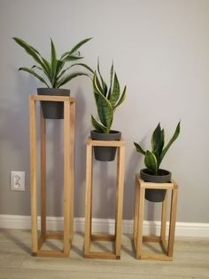 three wooden plant stands with plants in them