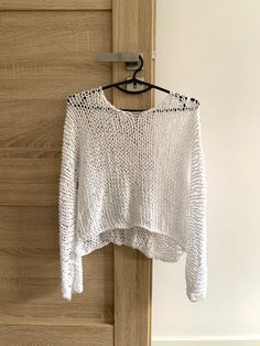 a white sweater hanging on a wooden door