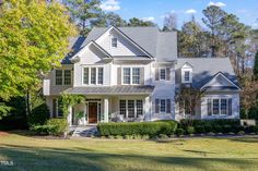 a large white house surrounded by trees and grass