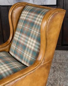 a brown leather chair with plaid upholstered seat