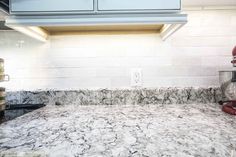 a kitchen counter with white marble and blue cabinets