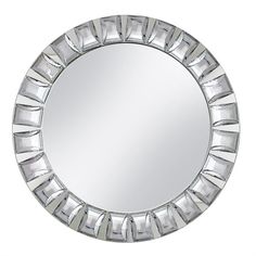 a round mirror that is on top of a white wall and has silver trim around the edges