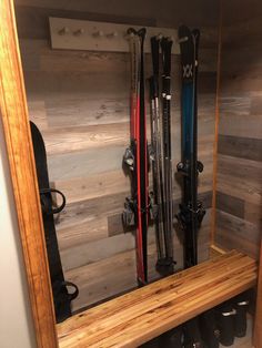 there are many skis in the mirror on this shelf, and one is leaning up against the wall