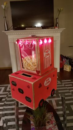 an open box sitting on top of a table with popcorn in it and lights coming from the inside