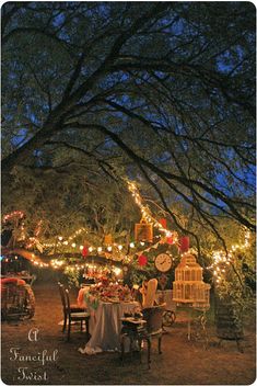 an outdoor dining area is lit up at night with fairy lights strung across the trees