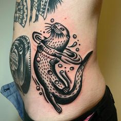 a woman's stomach with an otter tattoo on it