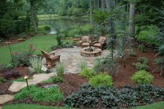 an outdoor patio with chairs and fire pit surrounded by trees, shrubs, and flowers