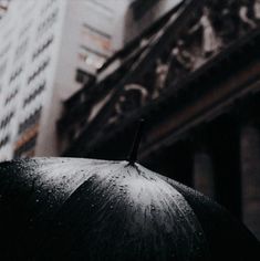 an open umbrella in front of a tall building on a rainy day with rain drops