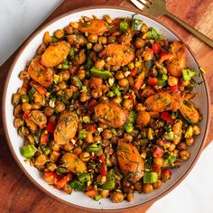 a white plate topped with chickpeas and veggies next to a fork