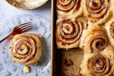 a pan filled with cinnamon rolls on top of a glass plate next to a fork