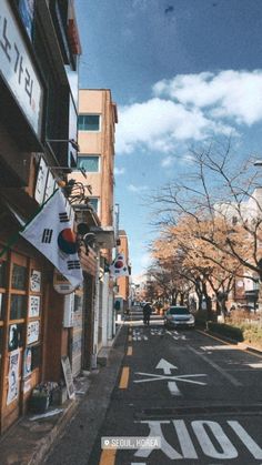 an empty street with buildings and signs on the side walk, in front of a blue sky