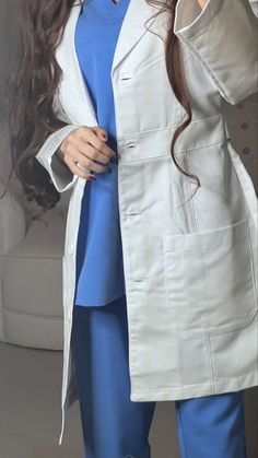 a woman with long hair wearing a white lab coat and blue pants is posing for the camera