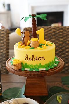 a yellow cake with a monkey on top and the number one in front of it