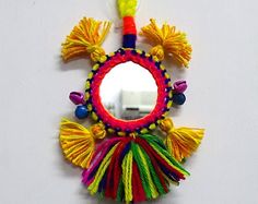 a colorful mirror hanging on the wall with tassels