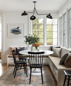 a dining room table with four chairs and a bench in front of a window that overlooks the woods