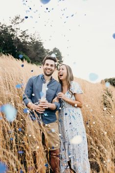 a man and woman standing in tall grass with confetti