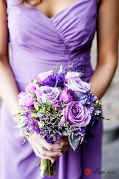 a woman in a purple dress holding a bouquet of flowers