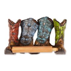 four cowboy boots are lined up on a wooden stand with a rolling board in front of them