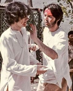 two men standing next to each other with red paint on their face and one holding something in his hand