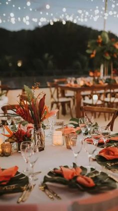 the table is set with orange napkins and place settings for an outdoor wedding reception