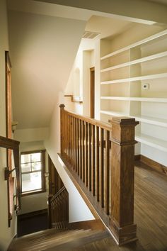 an empty room with wooden stairs and white bookshelves