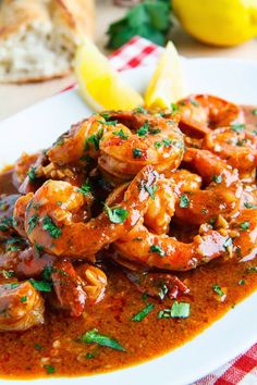 a white plate topped with shrimp covered in sauce and garnished with parsley