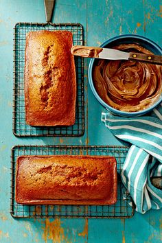 two loafs of banana bread on cooling racks next to a bowl of peanut butter