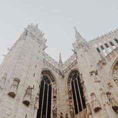 looking up at the top of two tall buildings with gothic architecture on each side and an airplane flying in the sky above